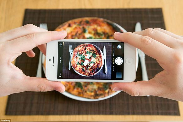 someone taking a photo of pizza on phone